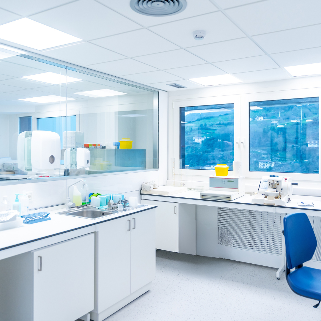 Modern laboratory with white cabinets, blue chair, and large windows.